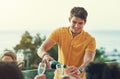 I guess everyone is thirsty for a drink then. a handsome young man pouring a bottle of champagne while his friends hold Royalty Free Stock Photo