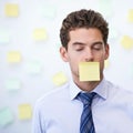 I had to sign a confidentiality agreement. a young office worker with a sticky note stuck over his mouth. Royalty Free Stock Photo