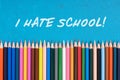 I hate school written above colored pencils on blue background Royalty Free Stock Photo