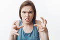 I hate you. Close up portrait of negative handsome european young woman with dark hair in blue shirt looking with mad