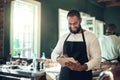 I have clients from all over the world. a handsome young barber standing alone and using a digital tablet in his salon. Royalty Free Stock Photo