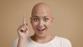 Bald-Headed Lady Pointing Finger Up Having Idea Over Beige Background