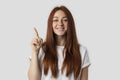 I have an idea! Beautiful redhead woman keeping finger pointed upwards, showing something above her head, making gesture with Royalty Free Stock Photo