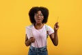 I have idea. Creative black female student raising pencil up and exclaiming eureka on yellow studio background Royalty Free Stock Photo