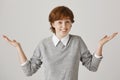 I have no clue. Portrait of carefree cute redhead female model with freckles shrugging and standing with spread hands