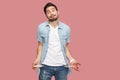 I have no money more. Portrait of sad bankrupt bearded young man in blue casual style shirt standing and showing his empty pocket Royalty Free Stock Photo