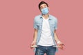 I have no money more. Portrait of sad bankrupt young man with surgical medical mask in blue shirt standing and showing his empty Royalty Free Stock Photo