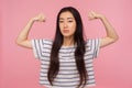 I have power! Portrait of successful bossy girl with brunette hair in striped t-shirt raising hands showing biceps