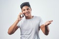 I have some good news for you. Studio shot of a young man talking on his cellphone while standing against a white Royalty Free Stock Photo