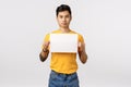 I have something say. Confident good-looking chinese modern guy in yellow t-shirt, holding blank piece paper over chest