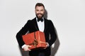 I have something for you. Handsome young man in full suit carrying a gift box and smiling while standing against grey background Royalty Free Stock Photo