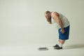 Puzzled thick guy staring at weight scales Royalty Free Stock Photo