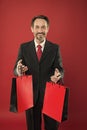 I help economy, I shop a lot. Happy shopper red background. Businessman hold shopping bags. Mature man enjoy shopping