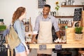 I hope the coffees to your liking. young barista serving a customer a cup of coffee at a cafe.