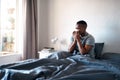 I hope this flu goes away soon. a handsome young man sitting in his bed and blowing his nose while suffering from a cold Royalty Free Stock Photo