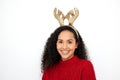 I hope I can cheer you up. Studio shot of a young woman wearing a reindeer antlers headband against a white background.