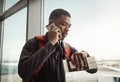 I hope I dont miss my flight. a handsome young man checking the time while making a call in an airport. Royalty Free Stock Photo