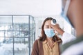 I hope you dont have a fever. a young woman wearing a mask and getting her temperature checked by her doctor in the