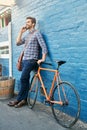 I just wheeled up to the cafe. a handsome young man leaning against a wall with his bike talking on a cellphone. Royalty Free Stock Photo