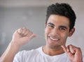 I know whats good for my teeth. Portrait of a happy young man flossing his teeth at home.