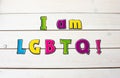 I am LGBTQ! Positive affirmation, statement. Bold neon letters on white table background