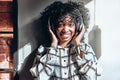 I like music!A beautiful african american woman holds headphones and listens to her favorite music. A woman is standing near a Royalty Free Stock Photo