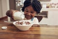 I like my breakfasts very milky. Cropped shot of an adorable little girl pouring milk into her cereal bowl at home. Royalty Free Stock Photo