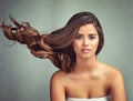 I like my hair with a bit of kink. Studio portrait of a beautiful woman with long locks posing against a grey background Royalty Free Stock Photo