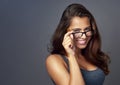 I like what I see. Studio portrait of an attractive young woman peering over her glasses against a grey background. Royalty Free Stock Photo