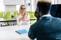 I listen to your suggestions. Portrait of confident qualified young afro american manager is sitting with his colleague female at