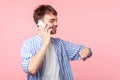 I`ll be late! Portrait of careless brown-haired man talking on phone and looking time on his wristwatches