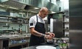 I love cooking. Male chef in apron, with black tattoos on his arms preparing salad in a restaurant kitchen. Royalty Free Stock Photo