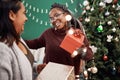 I love the gift, but I love you even more. two happy young women exchanging gifts during Christmas at home. Royalty Free Stock Photo