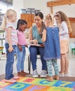 I love a good book as much as they do. Shot of a young woman reading to her preschool students. Royalty Free Stock Photo