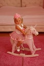 I love this horse. Small blond girl ride toy horse. Small child wear hair band. Little girl with long hairstyle. Hair