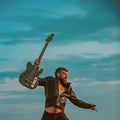 I love my guitar. Bearded man jump with guitar on blue sky. Hipster guitarist with beard on excited face fly in clouds Royalty Free Stock Photo