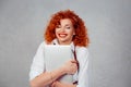 I love my laptop. Red head curly business woman in white shirt hugging computer smiling happy eyes closed isolated on gray