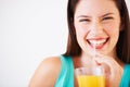 I love my orange juice. Portrait of an attractive young woman smiling while drinking orange juice through a straw. Royalty Free Stock Photo
