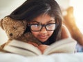 I love reading with teddy by my side. a cute little girl reading a book in her bedroom. Royalty Free Stock Photo