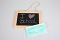 I love school text on slate blackboard with pandemic virus covid mask on grey background Royalty Free Stock Photo