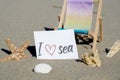 I LOVE SEA text on paper greeting card on background of beach chair lounge starfish summer vacation decor. Sandy beach Royalty Free Stock Photo