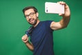 I love selfie! Handsome young man in shirt holding camera and making selfie and smiling while standing against green background