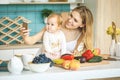 I love selfie! Young mother looking at camera and smiling, cooking and playing with her baby daughter in a modern kitchen setting Royalty Free Stock Photo