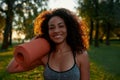 I love sport. Portrait of a young happy mixed race woman holding yoga mat and smiling at camera while standing in the Royalty Free Stock Photo