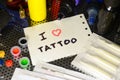 I love tattoo. The text is written on a small sheet of paper among various equipment for tattooing