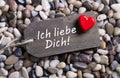I love you card with german text and a red heart on a wooden sign.