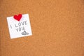 I love you handwriting lettering on 3 white papers pinned with 2 big red heart pegs and one small red heart pegs on cork board