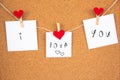 I love you handwriting lettering on 3 white papers pinned with 2 big red heart pegs and one small red heart pegs on cork board Royalty Free Stock Photo