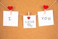 I love you handwriting lettering on 3 white papers pinned with 2 small red heart pegs and one big red heart pegs on cork board Royalty Free Stock Photo