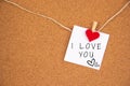 I love you with heart sign on white paper pinned with heart pegs on cork board Royalty Free Stock Photo